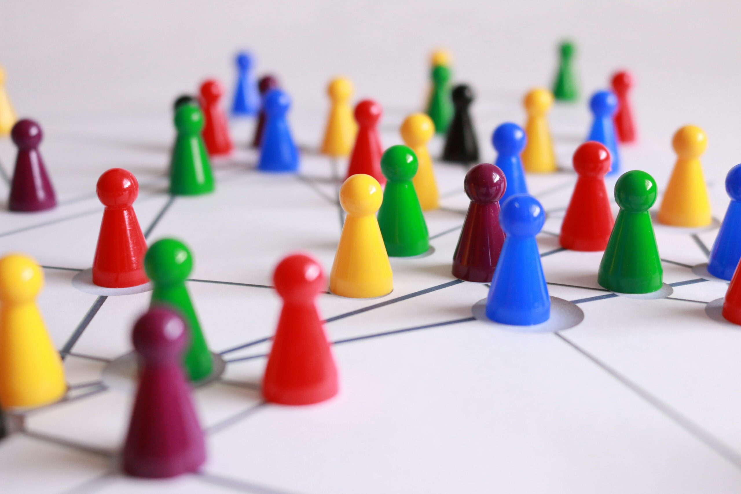 Close up stock image of many multicolored game pieces spread out over a map of network nodes or points.