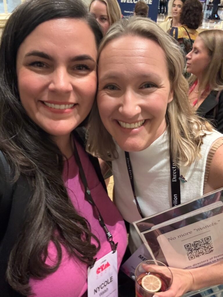 Photo of two women smiling with conference badges on 