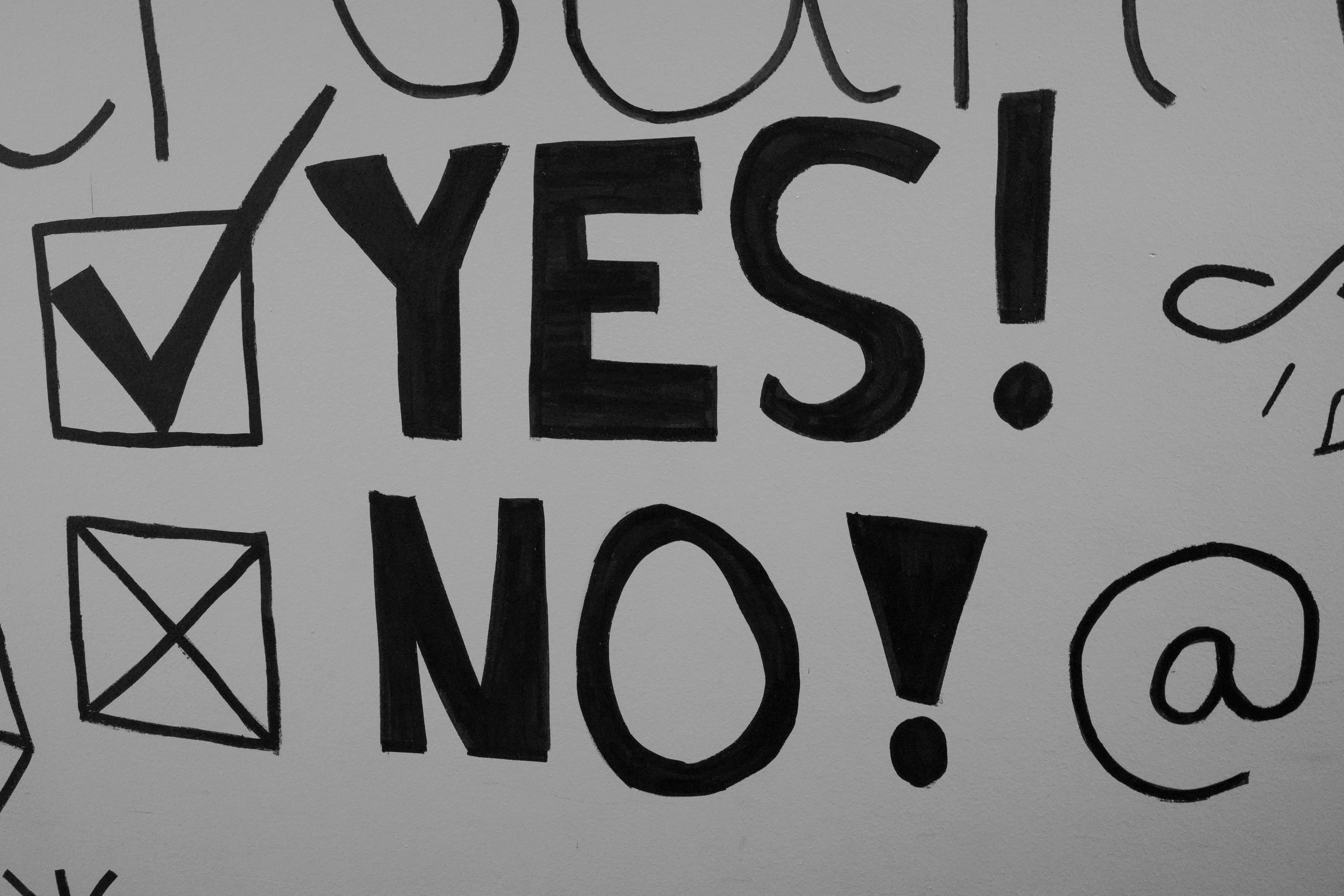 Stock photo of a handwritten sign featuring two checkbox options: "Yes!" and "No!" rendered in thick black ink on a white sign